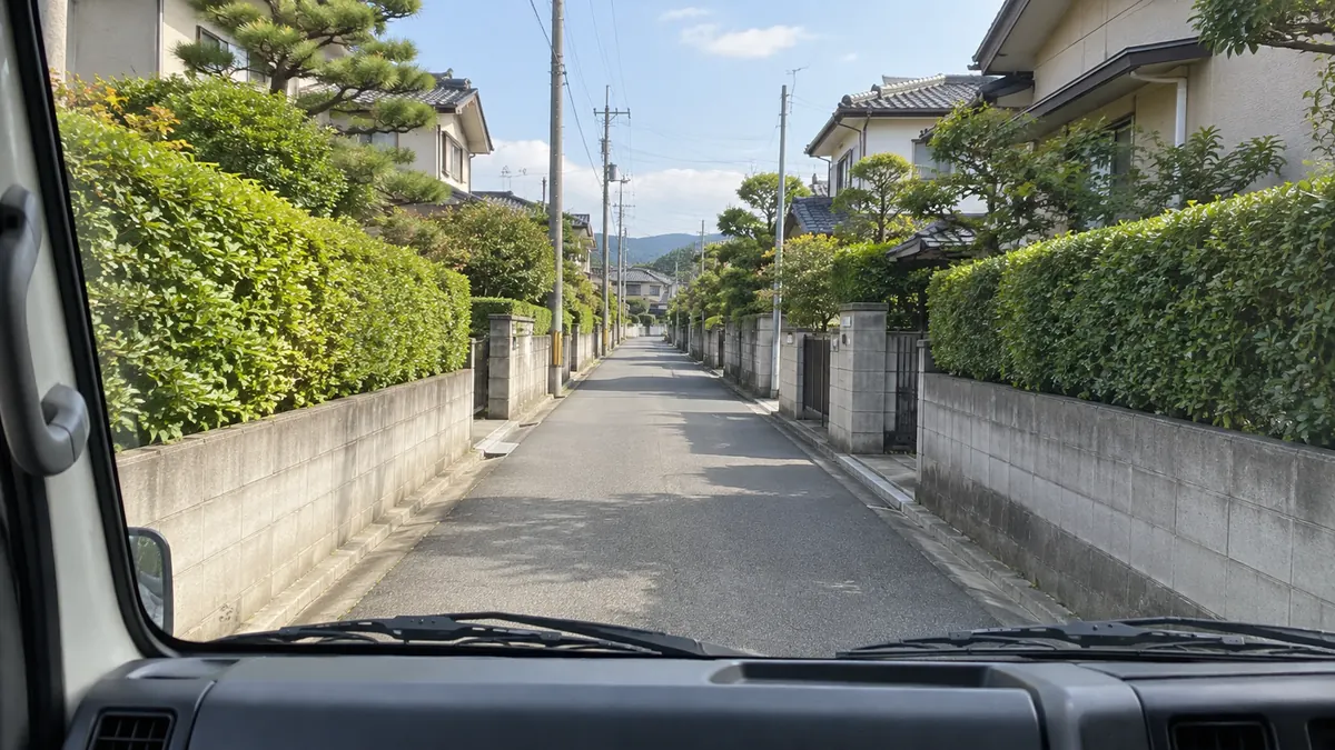 トラックの助手席から見た、住宅街のまっすぐな狭い道