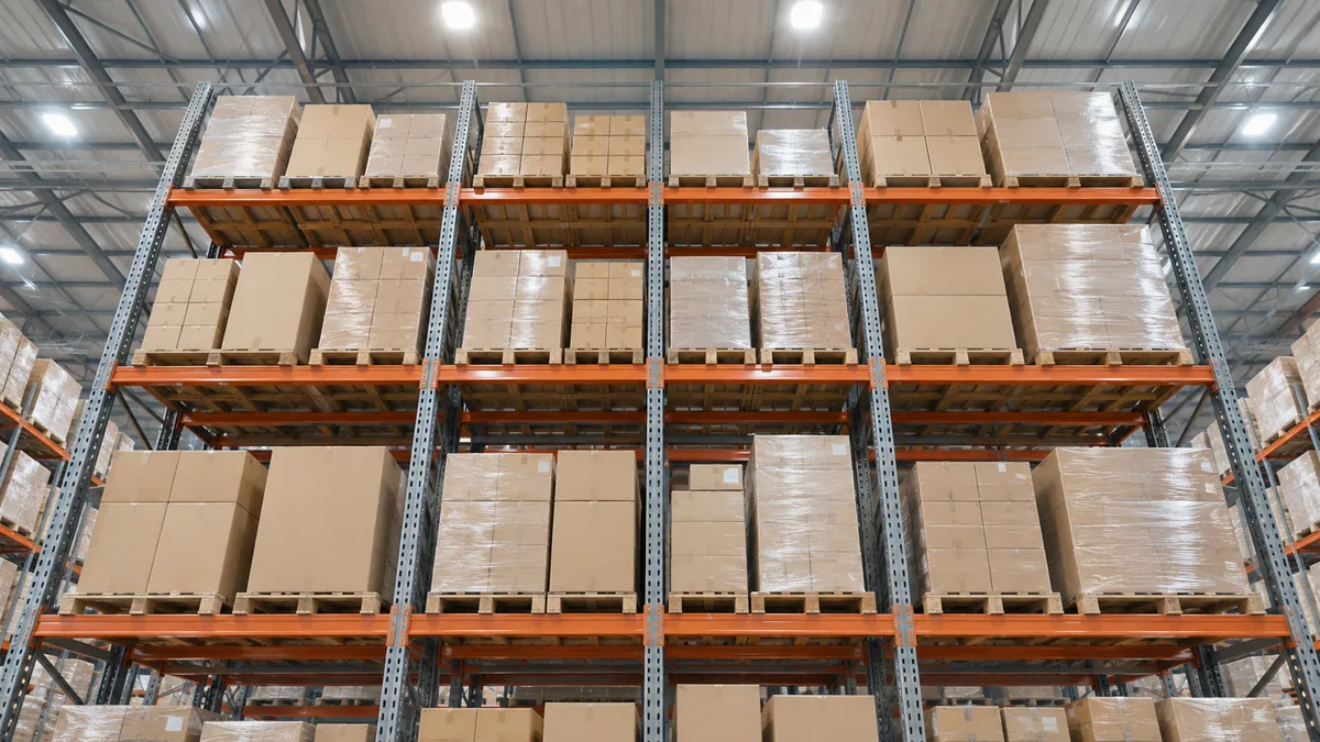 パレットの荷が4段に並んだ倉庫のラックを見上げたところ