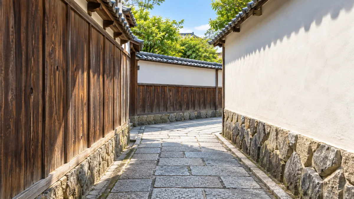 白い塀と板塀にはさまれ、先で曲がる石畳の細い路地