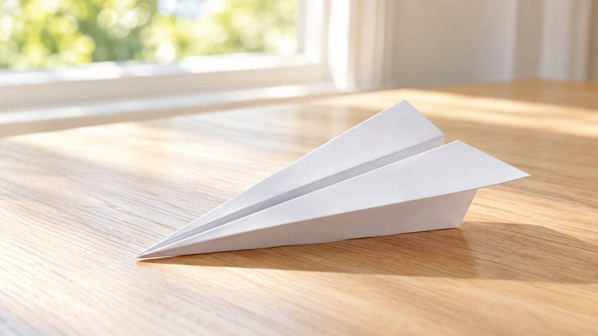 窓辺の木の机に置いた、白い紙飛行機